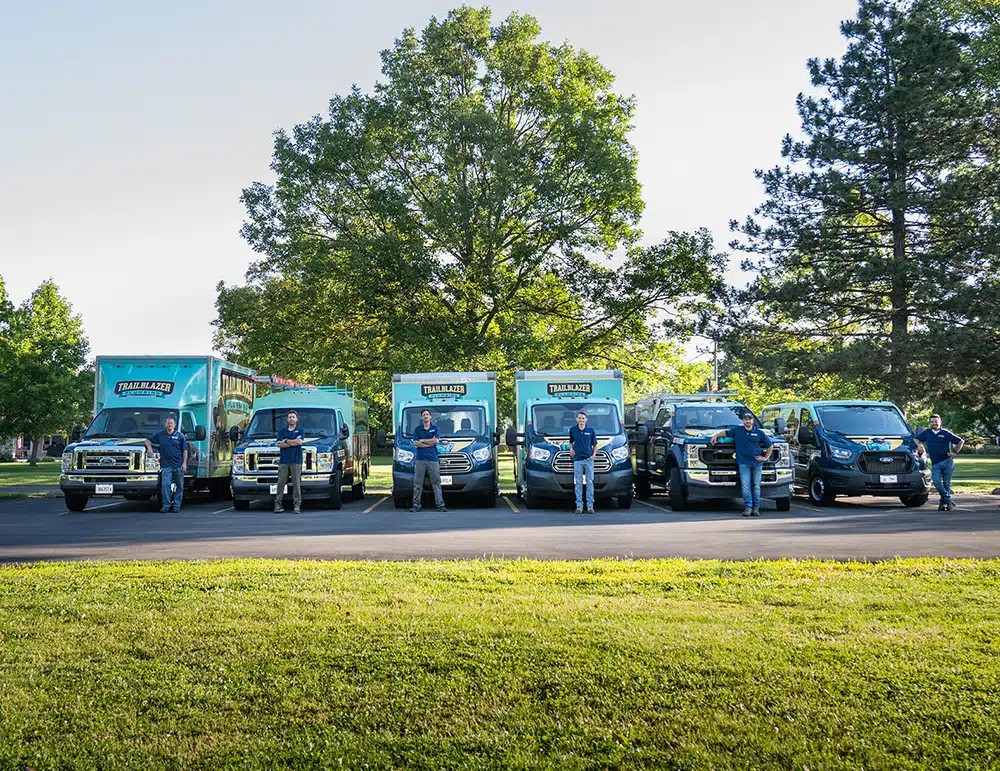 Trailblazer employees in front of service vans and trucks.