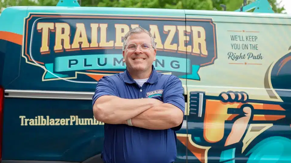 Tech smiling in front of Trailblazer Plumbing van in Lockport.